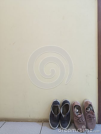 Two pairs of shoes leaning against the cream wall Stock Photo