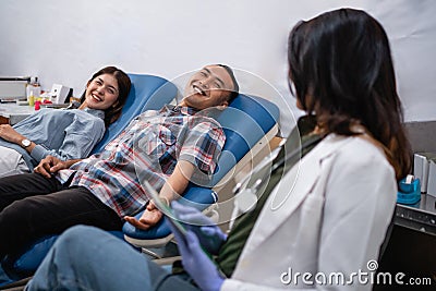 two patients lying in bed during a blood transfusion by a doctor Stock Photo