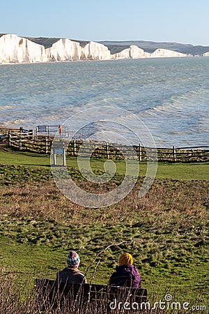 Two people admiring the view of Seven Sisters chalk cliffs at Hope Gap, Seaford, East Sussex on the south coast of England UK. Stock Photo