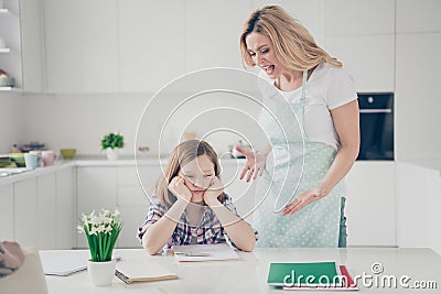 Two people angry furious mother scream her daughter kid sit table cant write homework lesson courses feel bored annoyed Stock Photo