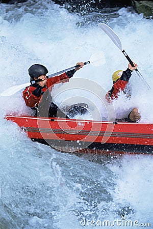 Two people paddling inflatable boat down rapids Stock Photo