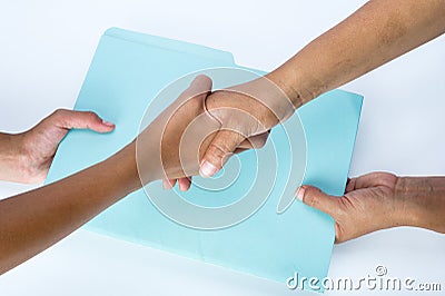 Two people shaking hands and exchanging documents as a sign of agreement Stock Photo