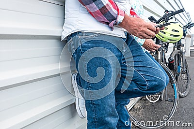 Two people standing with mobile phone in the handw, resting close the electric bicyles Stock Photo