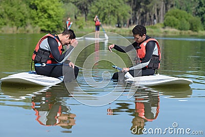 two people standup paddleboarding chating Stock Photo