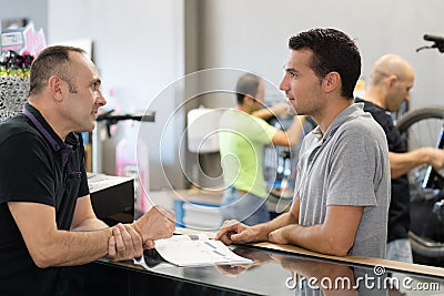 Two people talking over counter Stock Photo