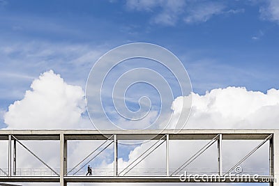 Two people walk on a suspended pedestrian bridge with a dramatic sky in the background in the government district of Berlin Stock Photo