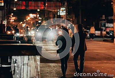 two people walking down the street at night, carrying hands and holding hands Editorial Stock Photo