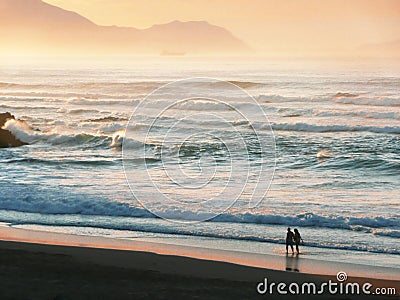 Two persons walking on beach Stock Photo