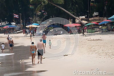 Two persons - young women and older man walk on sand beach keeping hands along the water. Sunny tropical day at Bang Thao beach Editorial Stock Photo