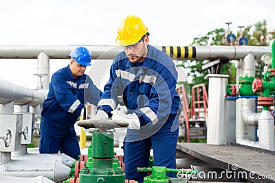 Two petrochemical workers inspecting pressure valves on a fuel tank Stock Photo