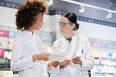 Two pharmacists comparing medicines regarding indications and side effects Stock Photo