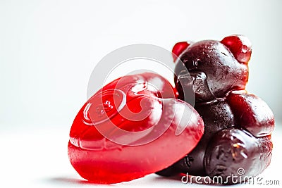 Two pieces of baby soap on a white background. One soap in the shape of brown teddy bear and another in the shape of a red heart Stock Photo