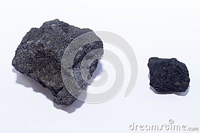 Two pieces of coal - large and small, lying next to a white background. Stock Photo