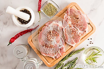 Two pieces of perfect pork neck to cook on a wooden kitchen board and marble countertop. top view. ingredients for Stock Photo