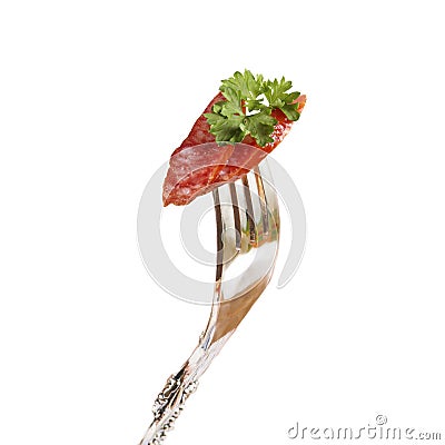 Two pieces of smoked sausage with parsley stuck on a fork. Stock Photo