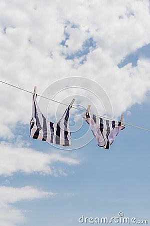 Two pieces swimsuit hanging in a clothes line against blue sky. Summer Stock Photo