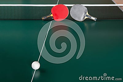 Two ping-pong rackets and a ball on a green table Stock Photo