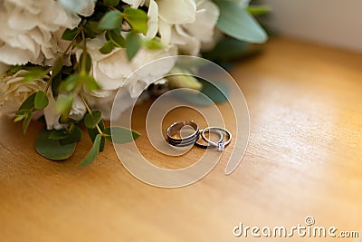 Two platinum wedding rings on wood background with flowers. Bride ring with diamonds. Shallow focus. Rustic wed concept Stock Photo