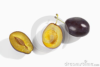 two plums one whole one halved on white background Stock Photo