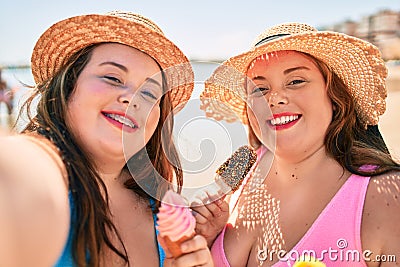 Two plus size overweight sisters twins women eating sweet ice cream at the beach on summer holidays Stock Photo