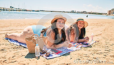 Two plus size overweight sisters twins women relaxing lying on a towel at the beach on summer holidays Stock Photo