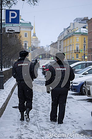 Two police officers patrol snowy streets in Russia. A man walks in front Editorial Stock Photo