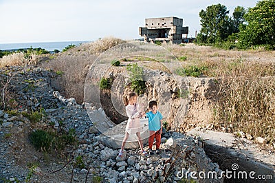 Two poor refugee children boy girl on ruins building destroyed by earthquake Stock Photo