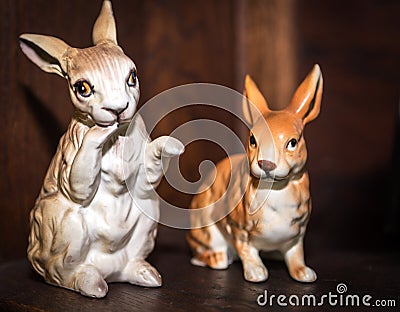 Two porcelain vintage bunny figurines with wooden background. Easter Concept Stock Photo