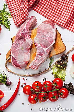 Two pork steak with meat knife and fork, fresh seasoning spices on dark rustic wooden background, top view Stock Photo