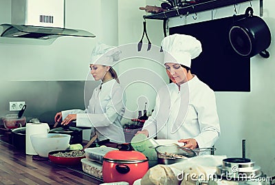 Two positive women chefs cooking food at kitchen Stock Photo