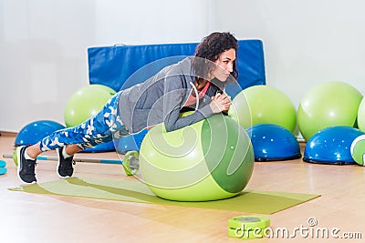 Two positive women doing plank exercise lying on balance ball in gym Stock Photo