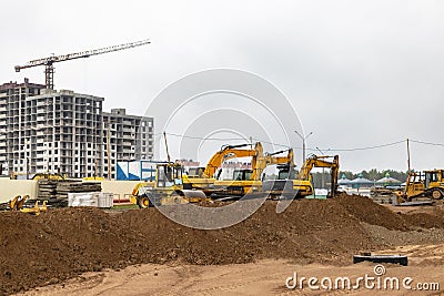 Two powerful excavators work at the same time on a construction site, sunny blue sky in the background. Construction equipment for Editorial Stock Photo