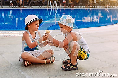 Two pre-school boys in hats and ice cream in a waffle cone . Children and summer Stock Photo