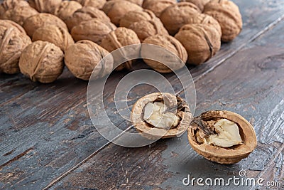 Two pretty halves of a ripe split walnut with a light, tasty core against a vintage wooden background. Stock Photo