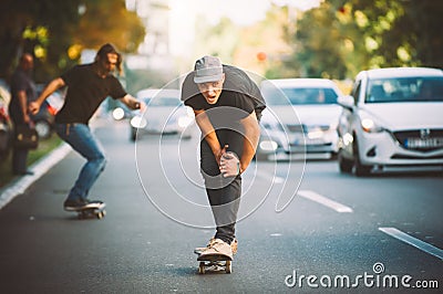 Two pro skateboard rider ride skate through cars on street Stock Photo