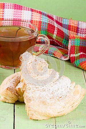 Two puff cookies with a cup of tea on a green wooden background Stock Photo