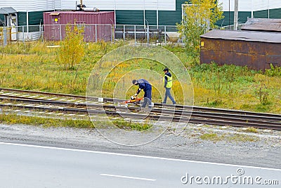 Two railroad workers are rolling the rails on a diagnostic trolley and checking the condition of the rails. Editorial Stock Photo