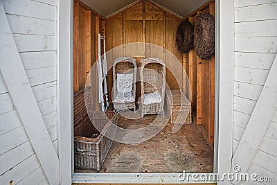 Two rattan garden chairs and rattan baskets stowed in the shed Stock Photo