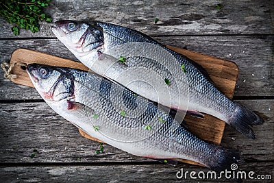 Two raw fresh sea bass on a cutting board with thyme Stock Photo