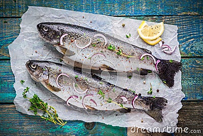 Two raw trouts on paper with thyme and lemon and red onion slices Stock Photo