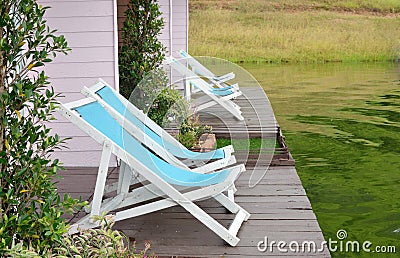 Two Recline chairs on dock facing a green lake. Stock Photo