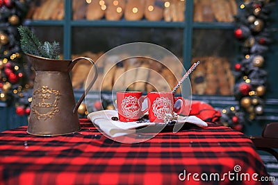 Two red cups of coffee on the table. Bakery exterior with Christmas decorations and fresh bread in showcase. Cozy outdoor bistro Stock Photo