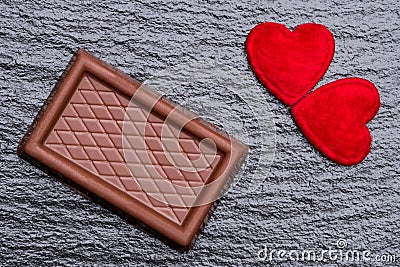 Two red fluffy hearts and a chocolate confection over rough black slate background Stock Photo