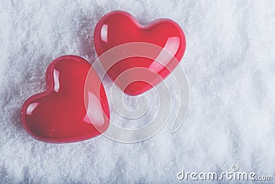 Two red glossy hearts on a frosty white snow background. Love and St. Valentine concept. Stock Photo