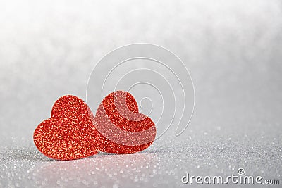 Two red hearts in glitter on a silver glitter background Stock Photo