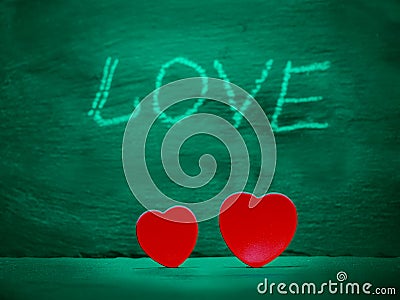 Two red hearts side by side and chalk sign love in the background. Saint Valentine abstract background Stock Photo