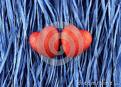 Two red painted polyfoam hearts on blue paper raffia background. Closeup. Stock Photo