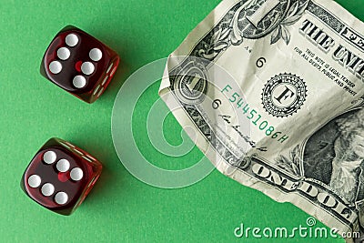 Two red playing dices with one dollar bill on green table. Luck and fortune concept Stock Photo