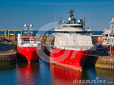 Two red and white offshore industry support / supply ships in Aberdeen Harbour. Taken on a sunny day with blue sky Editorial Stock Photo