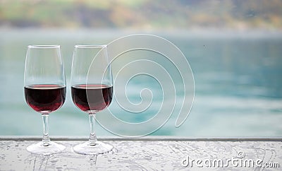 Two red wine glasses on bar over blur green lake background. Stock Photo